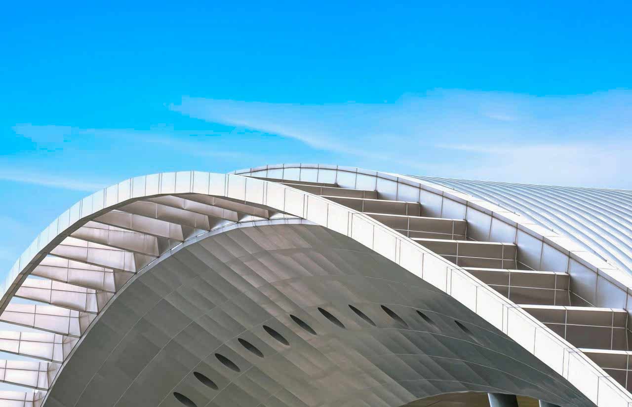 curve-metal-roof-of-modern-building-against-blue-sky-background.jpg
